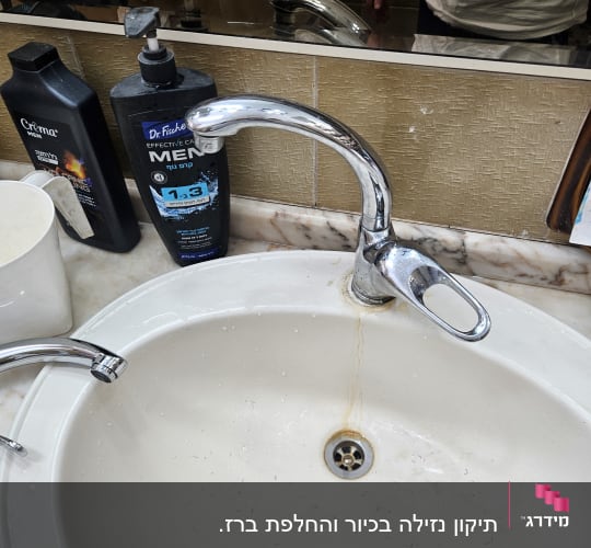 כיור עם ברז ומוצרי טיפוח בחדר אמבטיה
